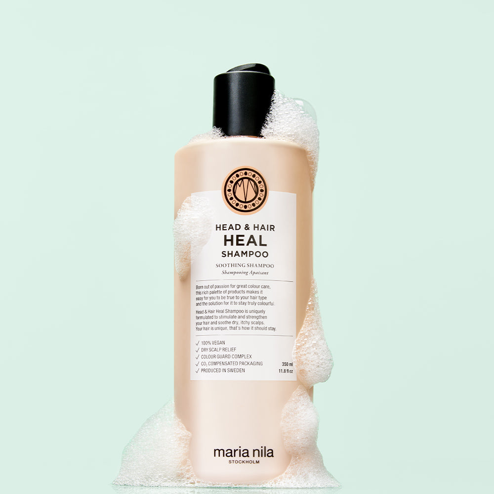 Head & Hair Heal Shampoo bottle with foam on light green background.